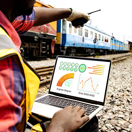 Engineers working on railway train station and using laptop for report data analysis from screen dashboard with walkie talkie for plan project. Rear of professional leadership of engineering work